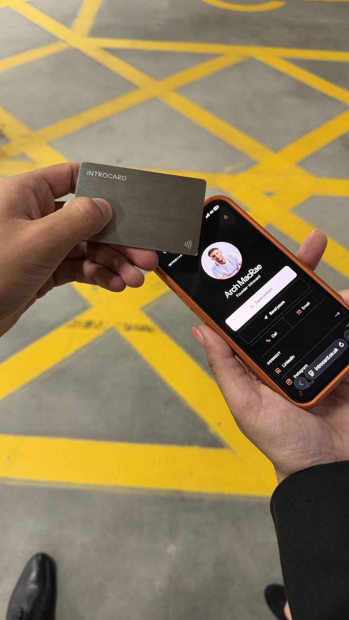 Introcard tapped against a phone, opening Arch MacRae's digital profile